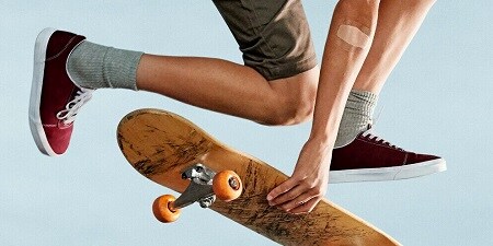 jongen op skateboard met een kompres op zijn elleboog
