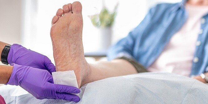 Verpleegkundige brengt verband aan op de hiel van de patiënt

