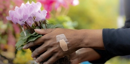 dame die bloemen plukt met een waterbestendige pleister op haar hand
