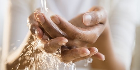 handen onder stromend kraanwater

